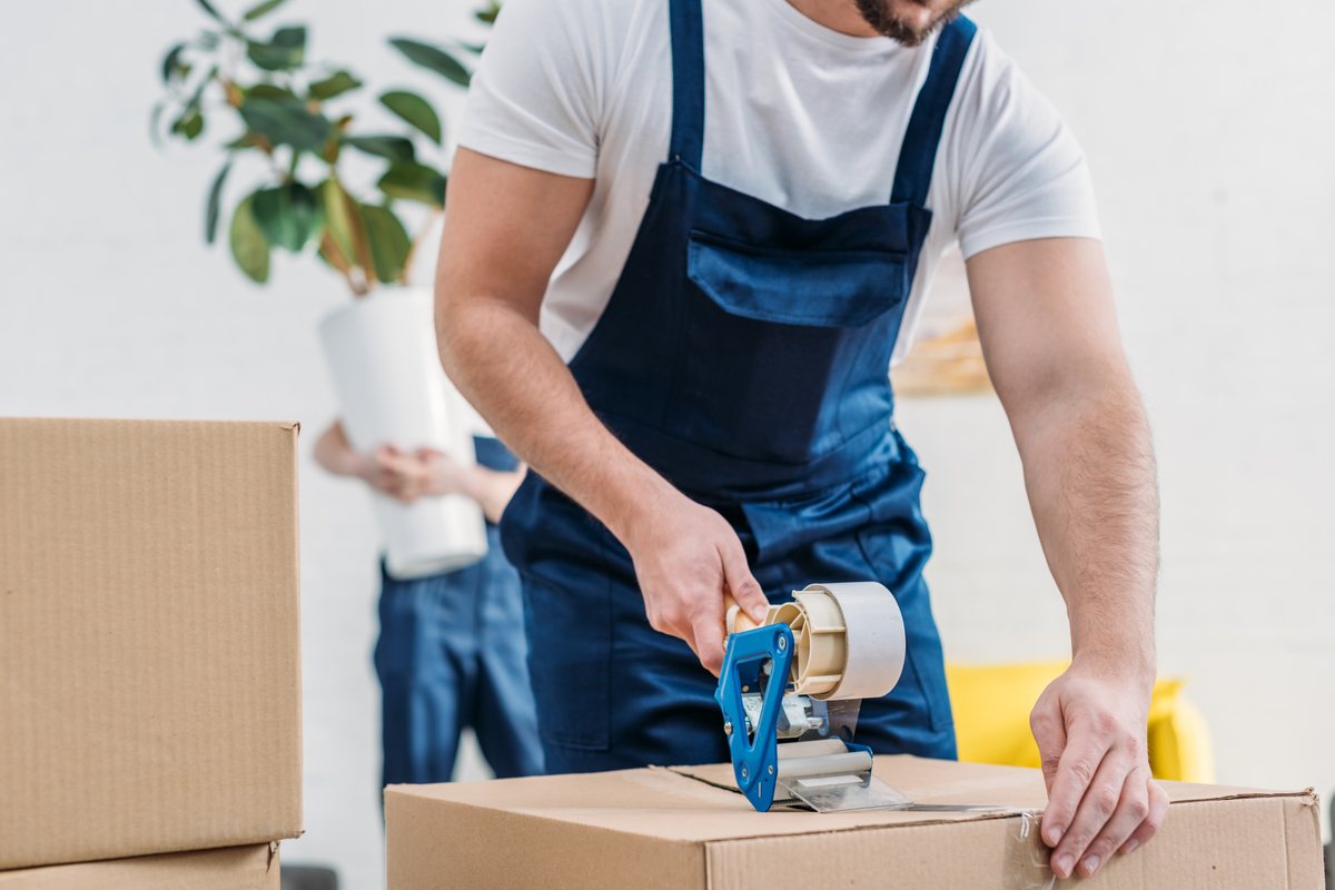 A mover taping a box shut