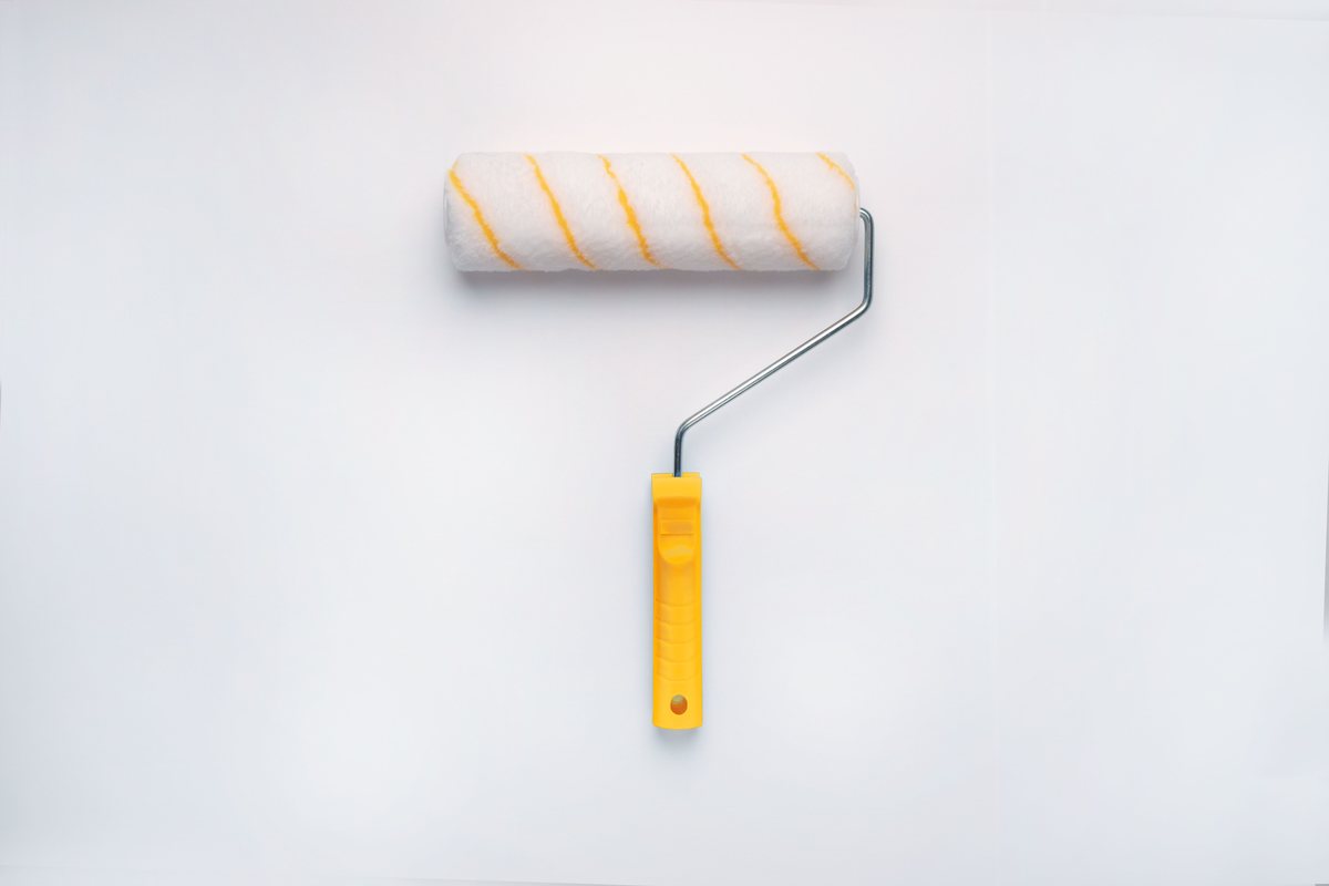A paint roller on a freshly painted wall